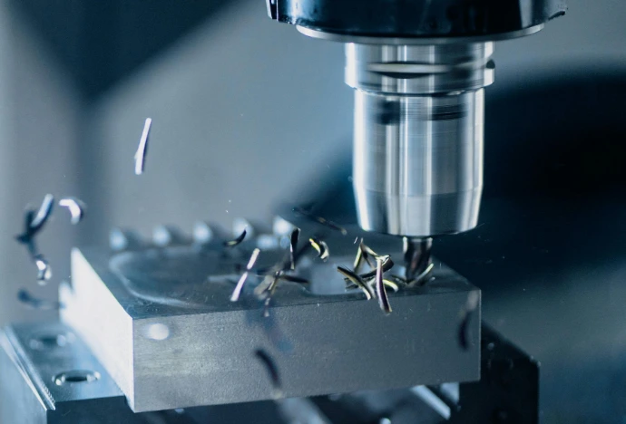 Fraisage CNC de précision sur bloc métallique avec copeaux, sur centre d’usinage en production industrielle.