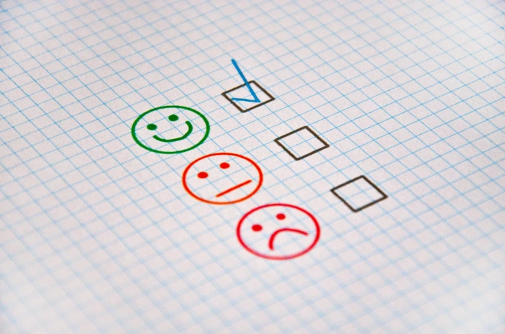 Évaluation de satisfaction client avec cases à cocher et icônes smiley, illustrant un questionnaire qualité.